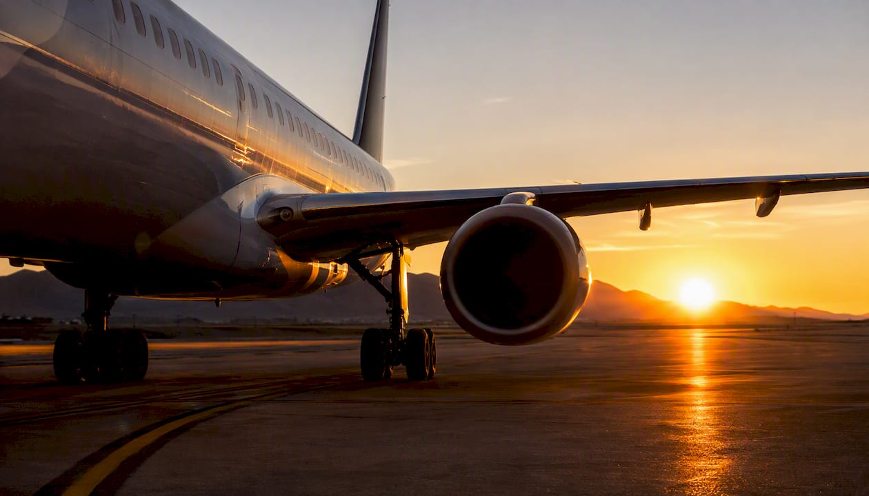 Airplane taxiing on runway at sunset