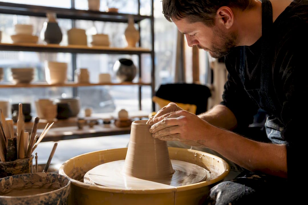 Hands shaping clay on potter’s wheel