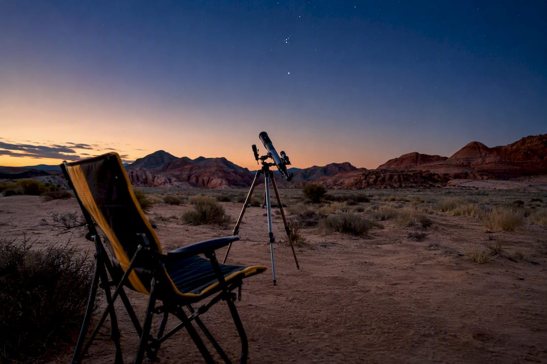 Desert stargazing setup at dusk with telescope